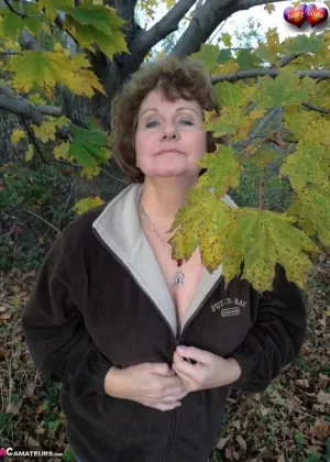 Пожилая женщина Грудастая Блисс обнажает свои большие натуральные сиськи под деревом осенью