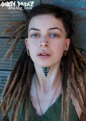 Одинокая девушка с крашеными волосами и пирсингом раздевается на своей домашней веб-камере