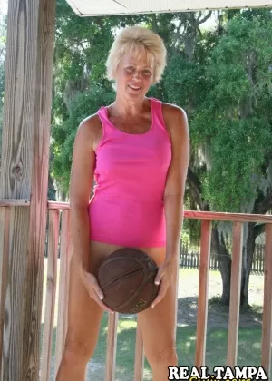 Женщина-культурист Джоанна Томас напрягает свои мышцы, снимая розовое платье