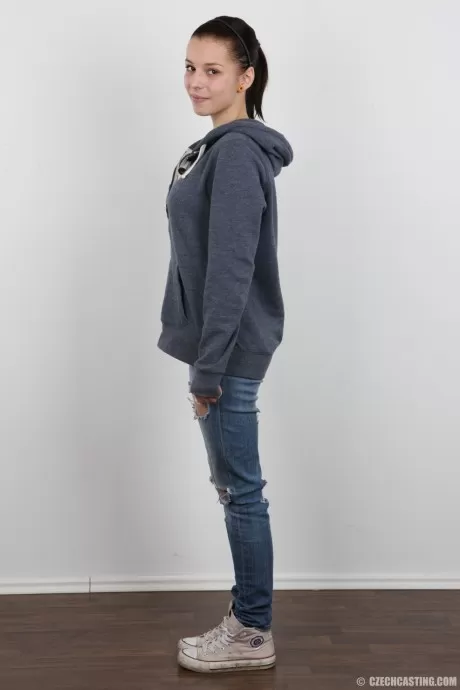 Молодая брюнетка снимает джинсы и лифчик, чтобы предстать в своем праздничном костюме