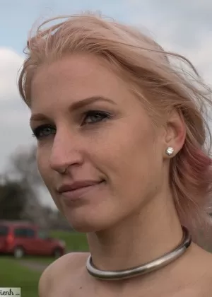 Самка Ариенх Отэм в ошейнике обнажает свои маленькие груди на травянистом берегу