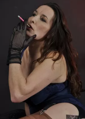 Mature woman Nylon Jane smokes while wearing sheer gloves and tan nylons