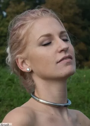 Девушка с воротником Arienh Autumn моделирует красный кожаный корсет, находясь в поле