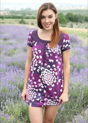 Красивая молодая девушка снимает платье, чтобы позировать обнаженной среди полевых цветов