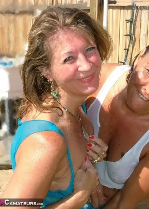 Mature amateurs engage in lesbian sex after getting wet in backyard by a pool