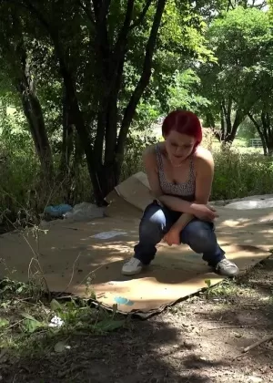 Одетая девушка Мистика садится на корточки, чтобы пописать у дороги в зимней одежде