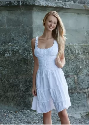 Стройная девушка со светлыми волосами и симпатичным личиком стоит голая после снятия платья