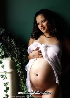 Одинокая девушка Брианна обнажает свой беременный живот на скалистом берегу реки