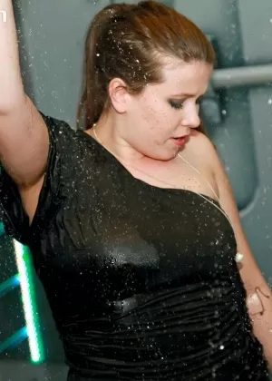 Одетые лесбиянки промокают под дождевальной системой во время танцев в клубе