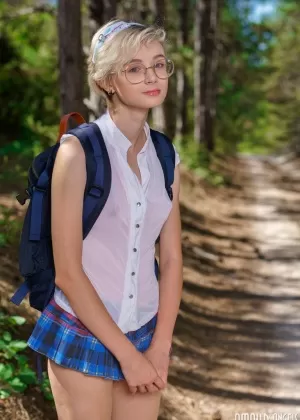 Молодо выглядящая девушка Азшара снимает школьную одежду на грунтовой дороге в лесу